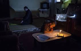 Dans le village d'Al-Moughraka, Ossama, 8 ans, fait ses devoirs à la lumière d'une bougie. (photo et légende: Le Parisien)