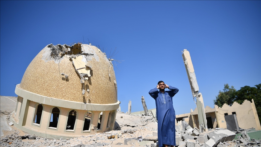 Un Palestinien de Gaza appelant à la prière devant une mosquée détruite par les bombardements israéliens